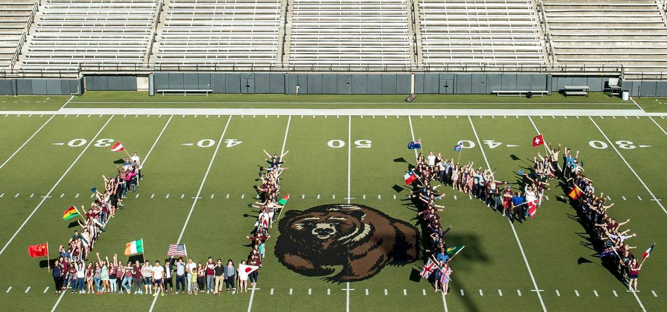 International students with flags on football field