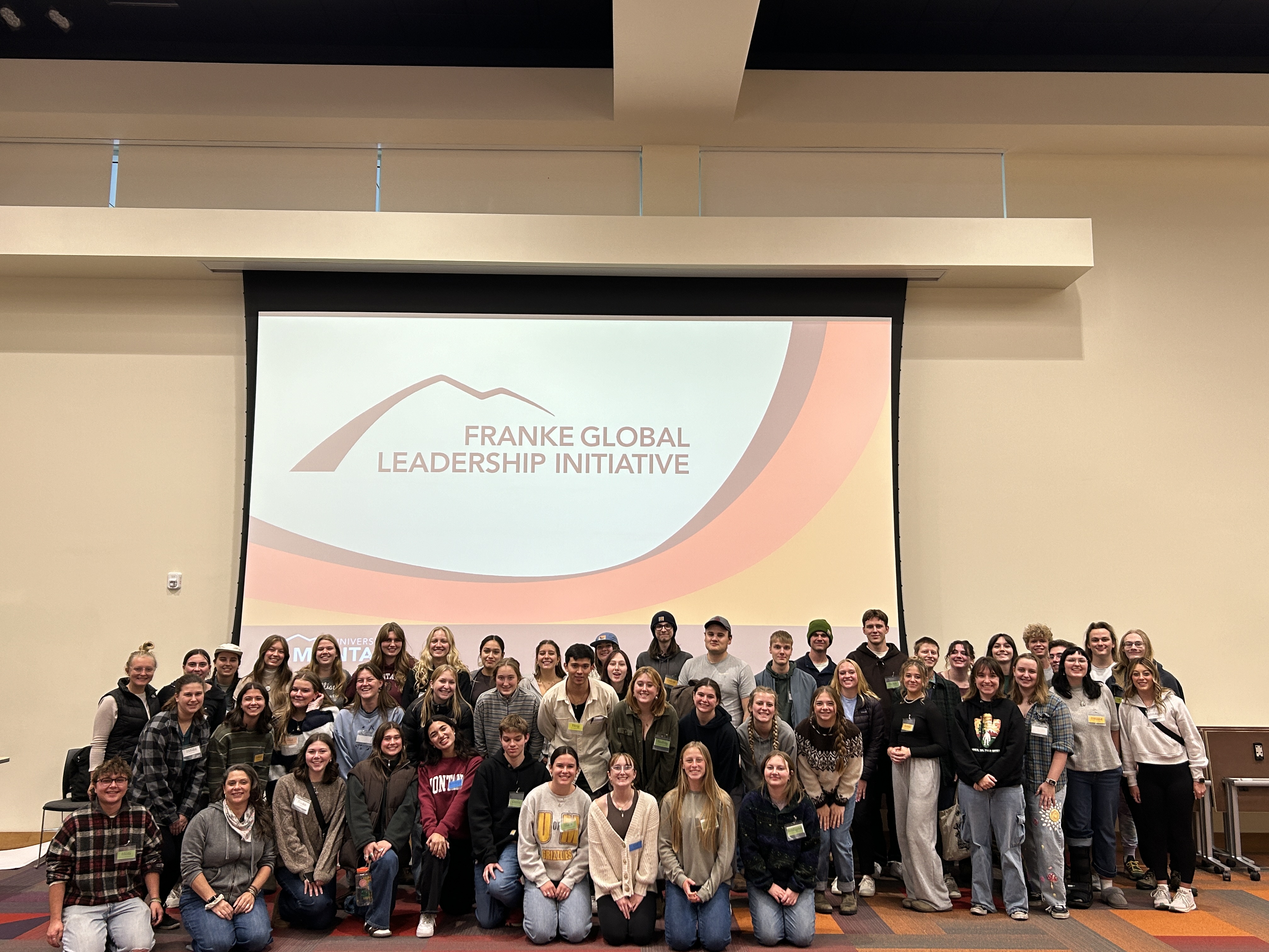 Group of 60 GLI students pose in the front of the room with retreat facilitator Shannon Stober