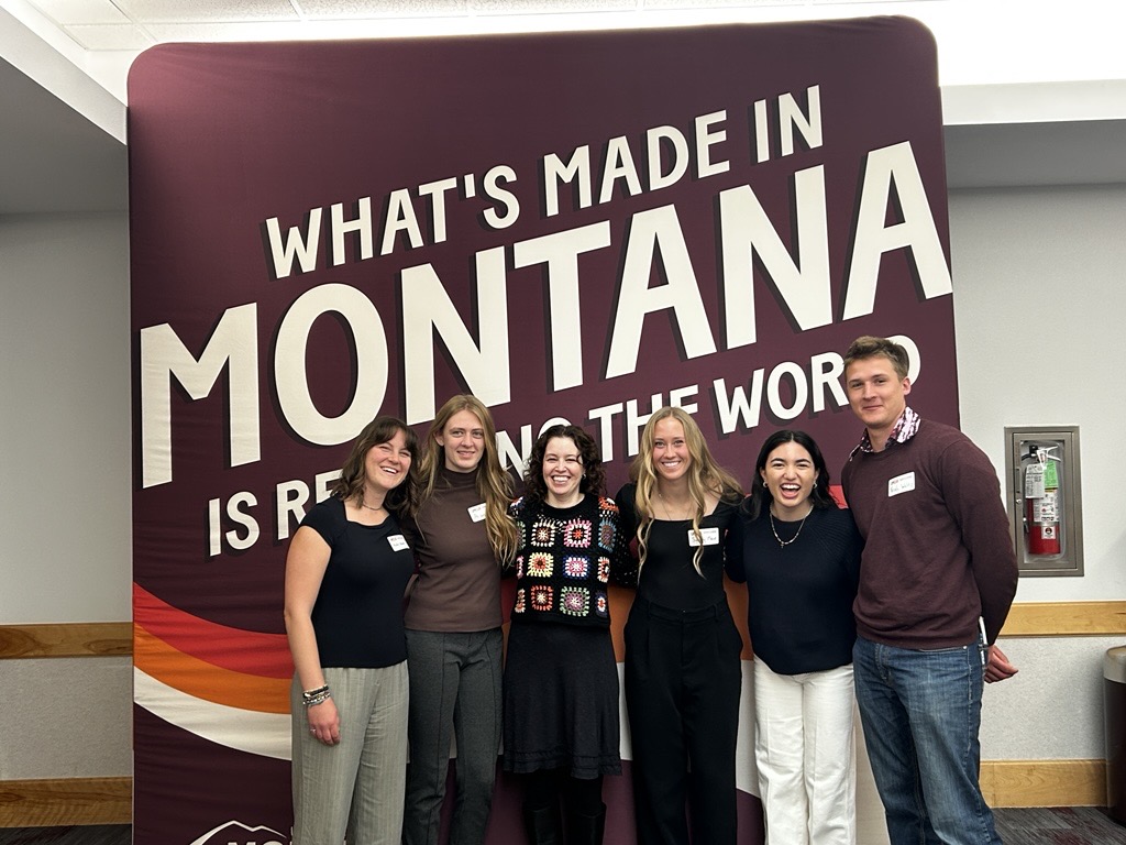 a group of students with a mentor in front of a banner