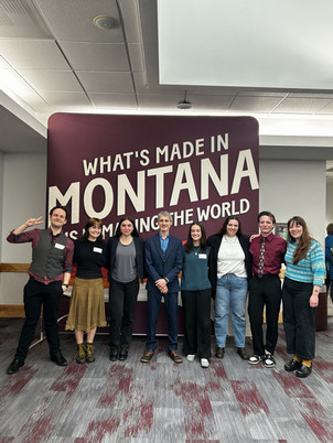 team of seven students stands with their mentor in front of a UM banner after presenting at the UM conference for undergraduate research