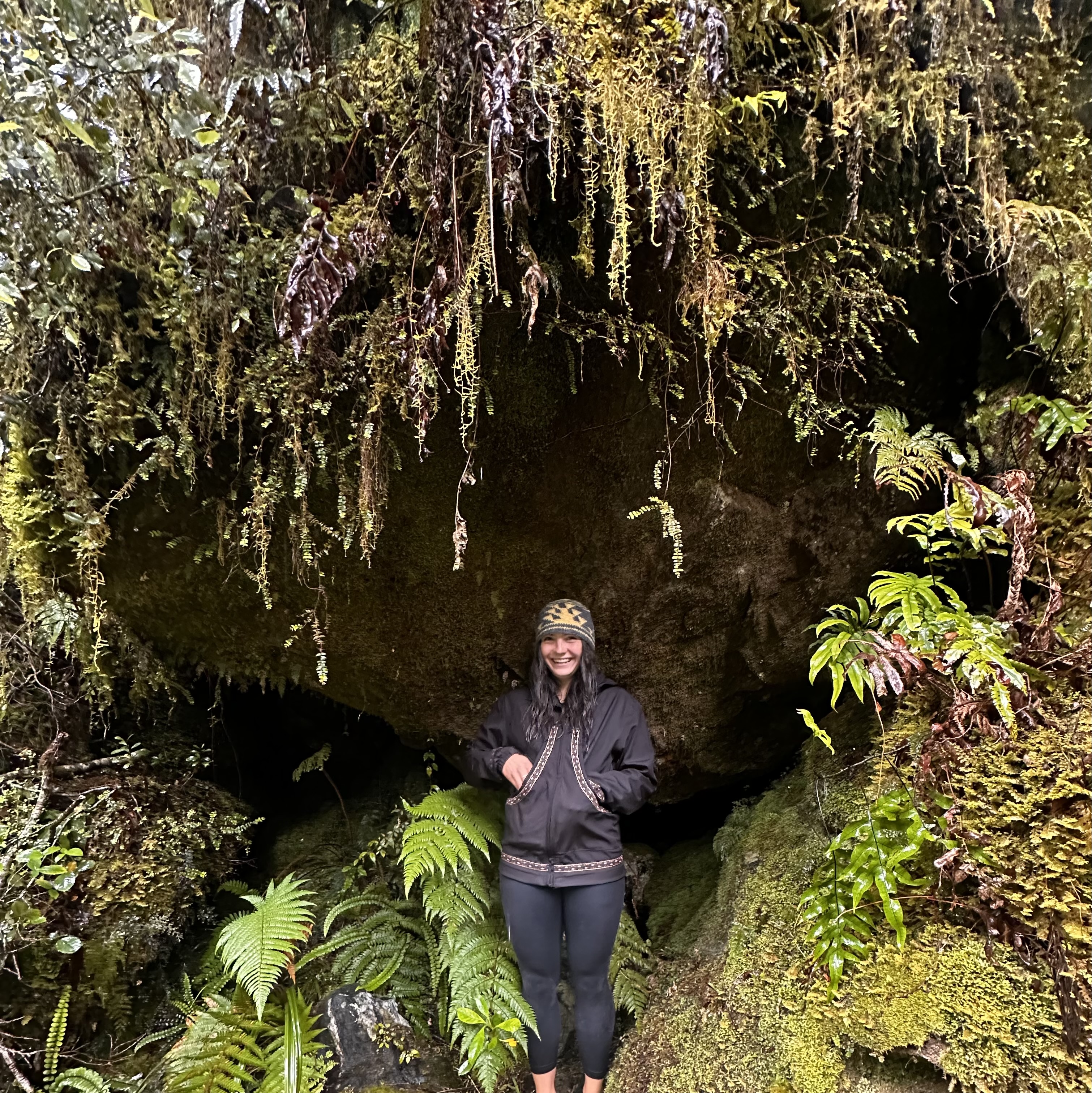 Female student stands in front of wall of moss dripping with water
