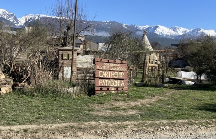 Mountains overlook a Patagonian farm in Argentina. A sign announces hostels in the area.