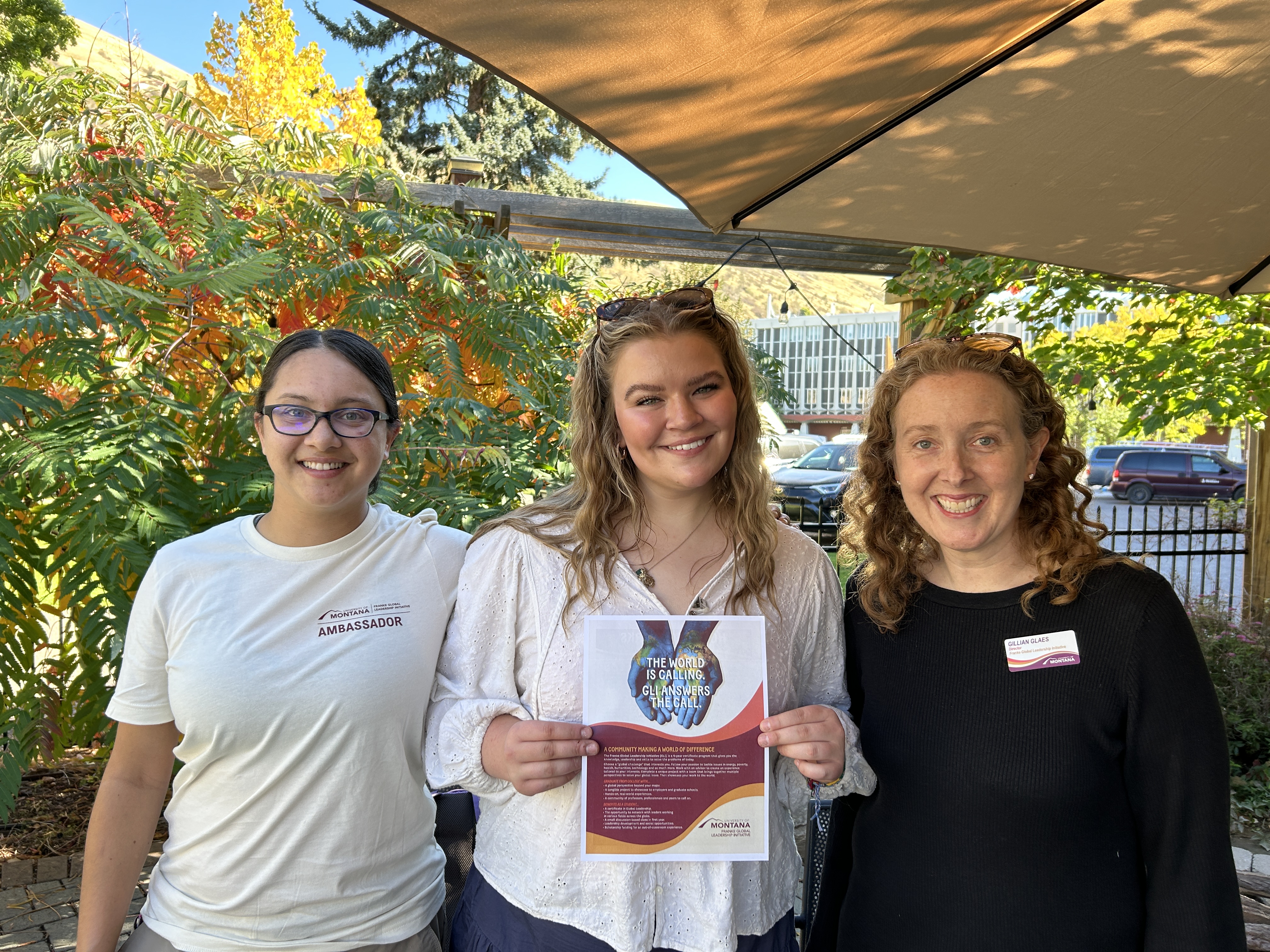 two student ambassadors stand with GLI director Gillian Glaes on the honors college patio