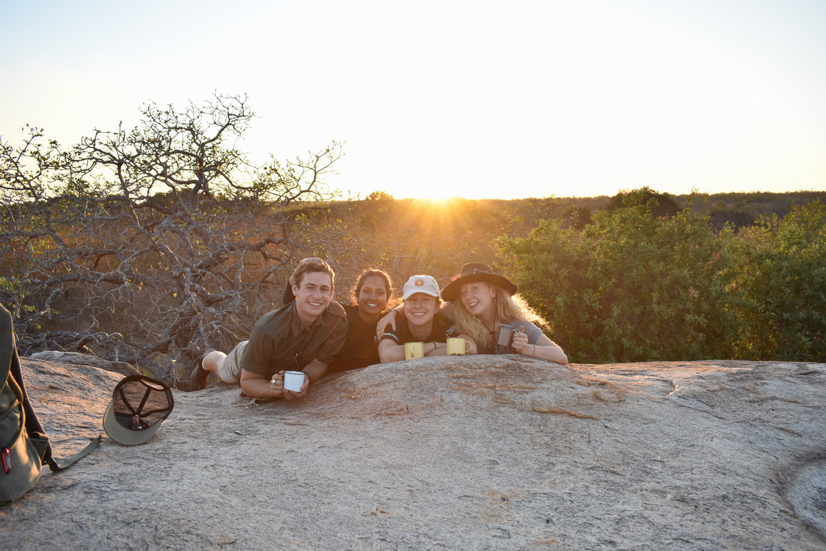 four individuals perched on a boulder drinking coffee in south Africa