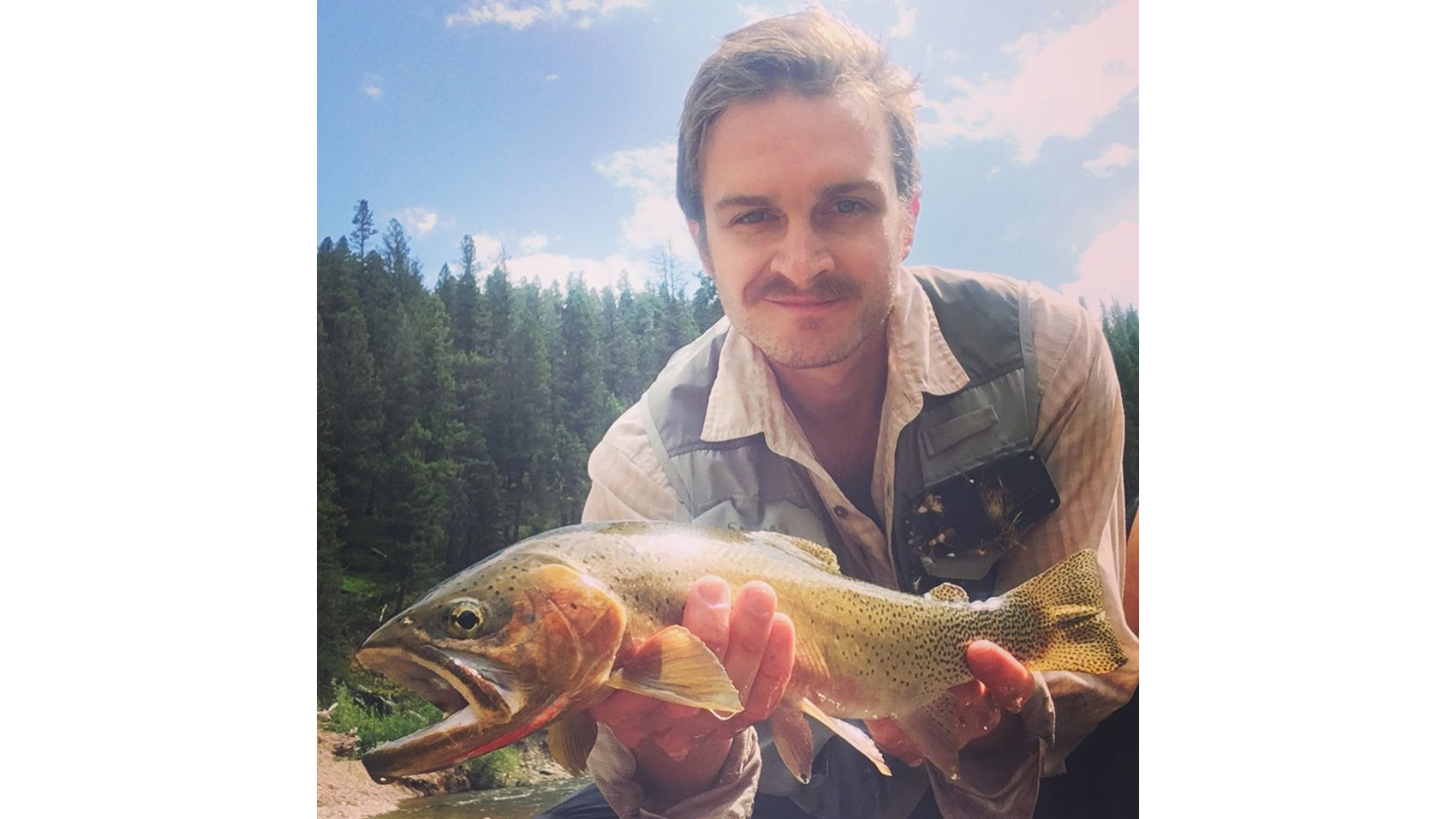 Joseph Denhert holding a trout fish.