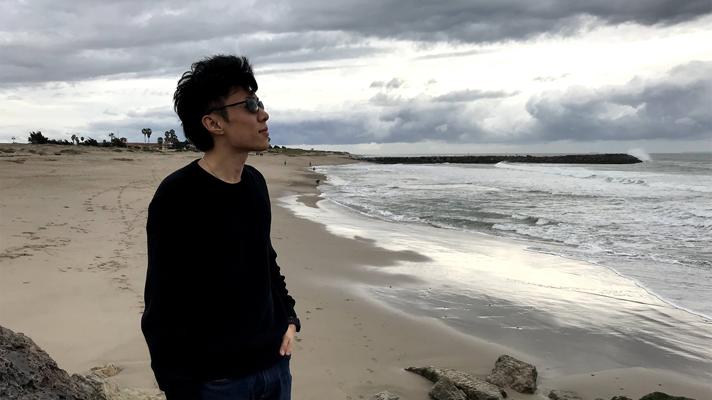 man stands on coastline and stares at the ocean
