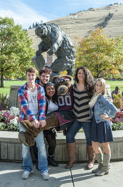 Students with University of Montana mascot Monte in front of grizzly statue