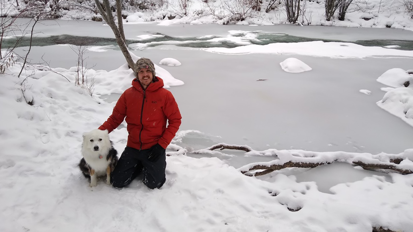 Zachary Lauffenburger by frozen river with dog