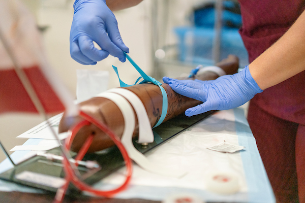 Nursing student working with practice IV arm