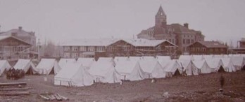 black and white picture of many tents outside a large building