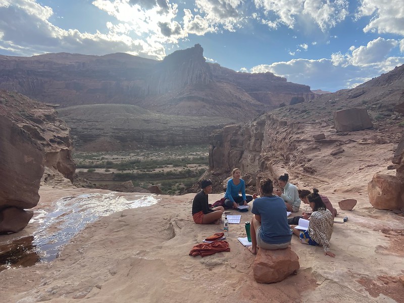 WRFI students sitting on desert outcropping in discussion.