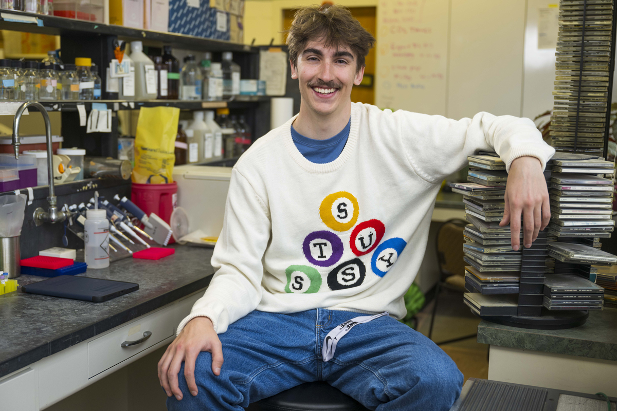 Wyatt Walter sitting in a lab with arm over CDs