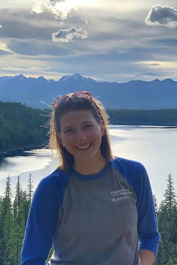 headshot of megan moore outside with a lake and mountains in the distant background