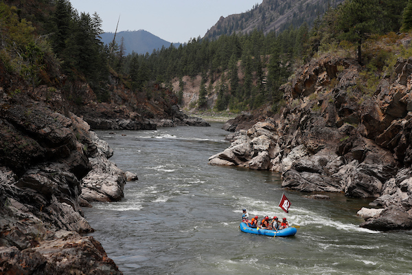 raft floating on river with people and UM flag