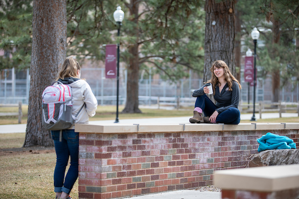 Two students talk, 6 feet apart