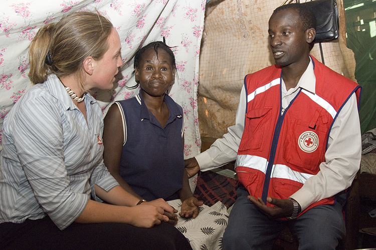 volunteer and Red cross staff workiing with woman