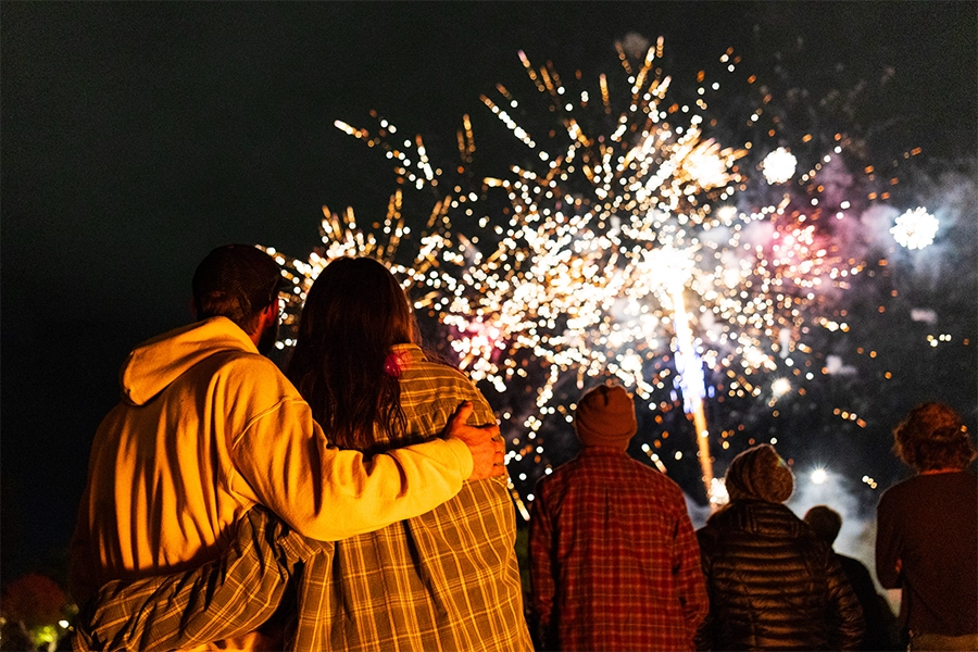 A couple hugs under fireworks at the UM Yell Night Pep Rally