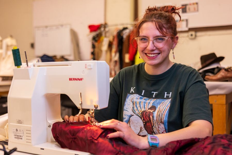 A student sits at a sewing machine