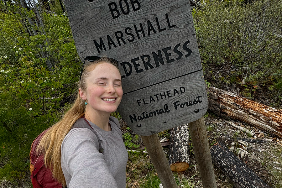 A selfie of Emma in front of the Bob Marshall Wilderness Trail sign