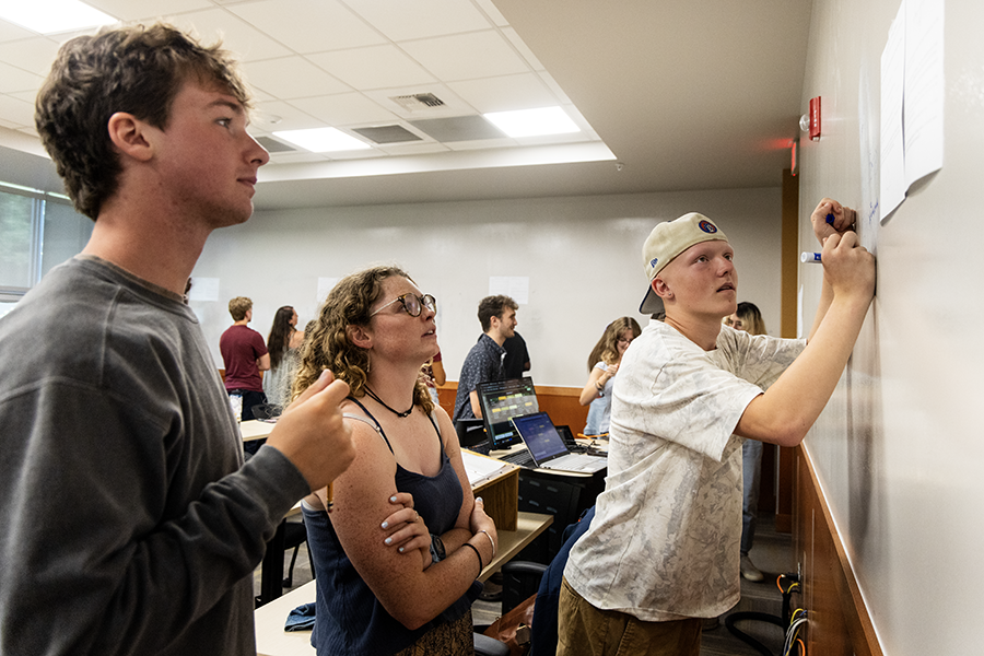 A picture of current students writing on a whiteboard 