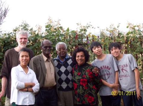 group of people standing together next to a large bush 