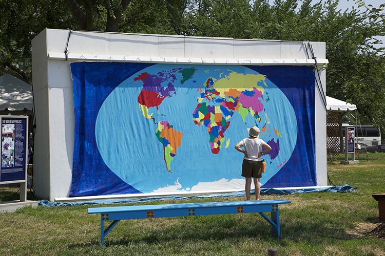person looking at a large hand-paited world map displayed outside