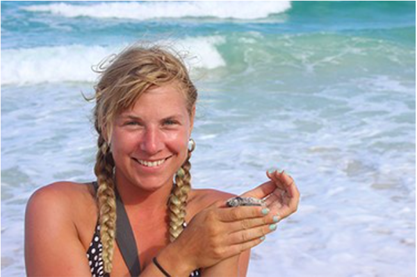 Lily on the beach holding a small sea turtle
