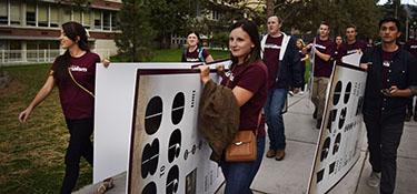 Students carry Centennial Signs across campus.