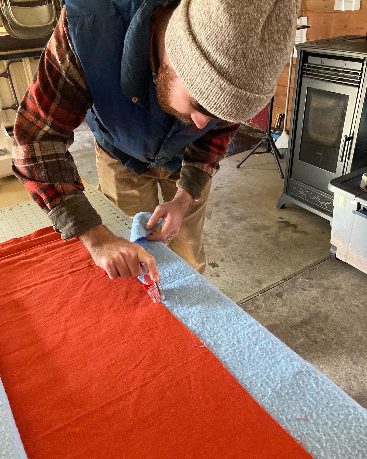 man cutting fabric to make insulated curtain