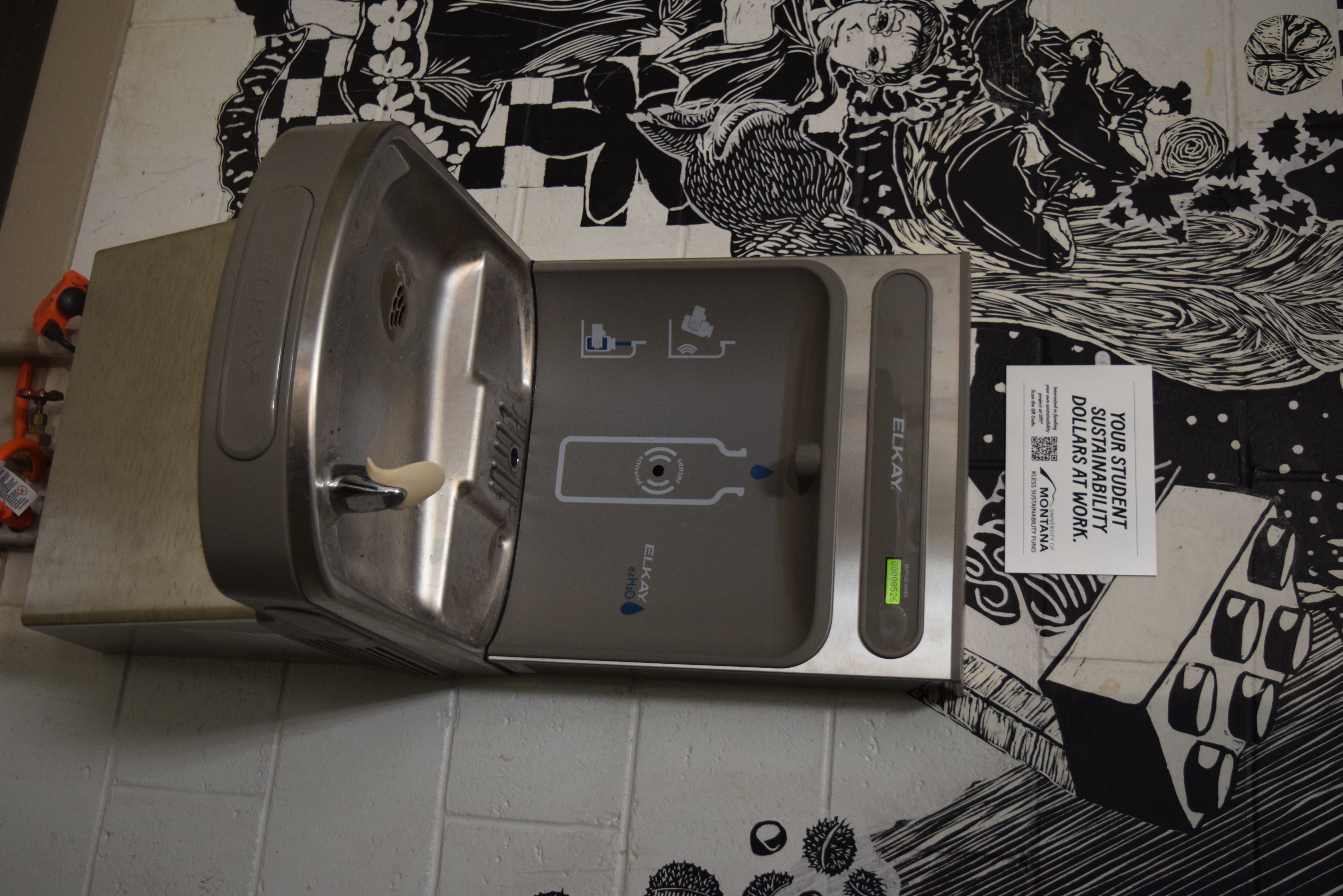 waterbottle filler in the fine arts building with black and white mural and kless signage
