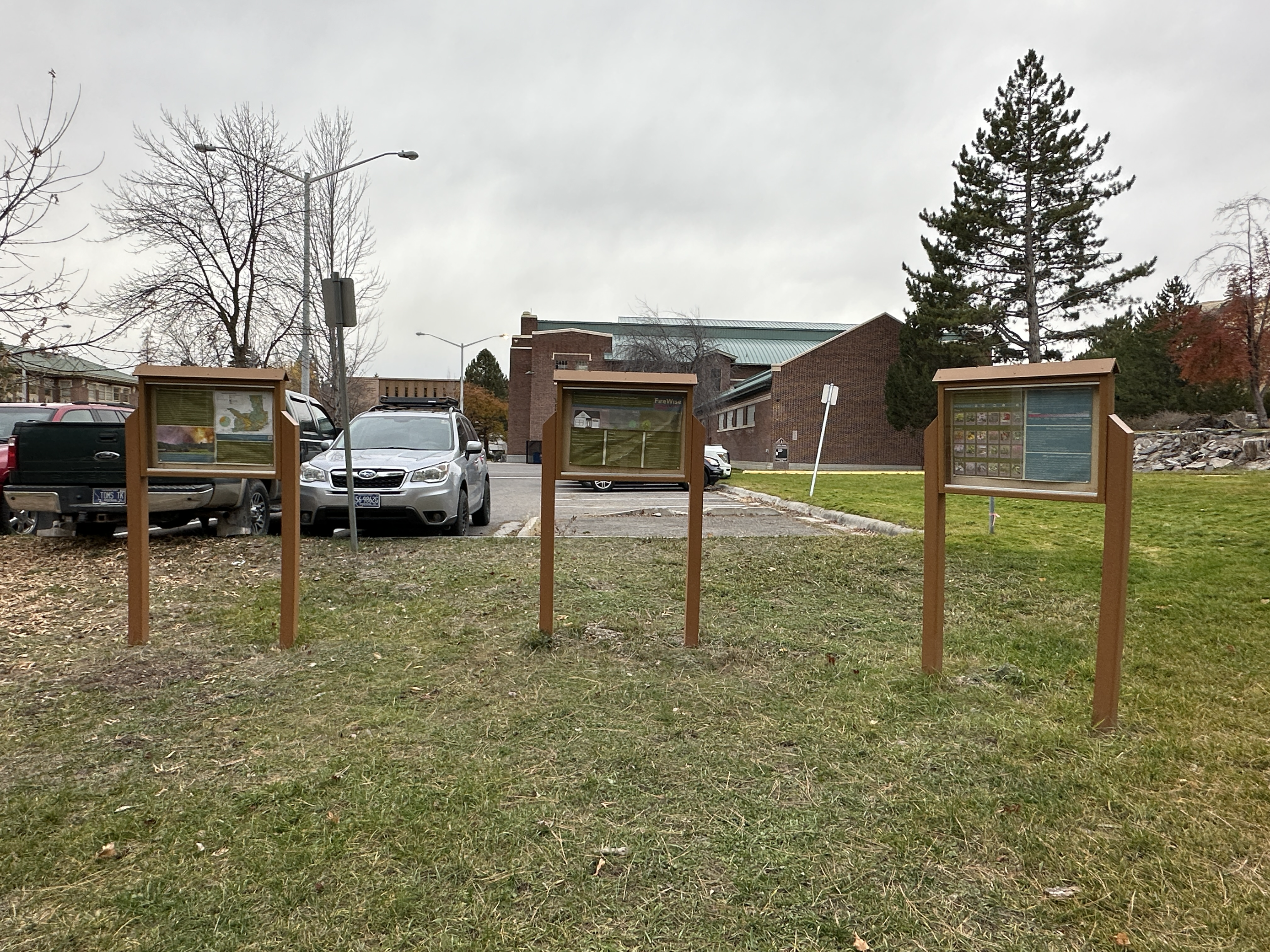 three signs sit in front of firewise garden on UM campus