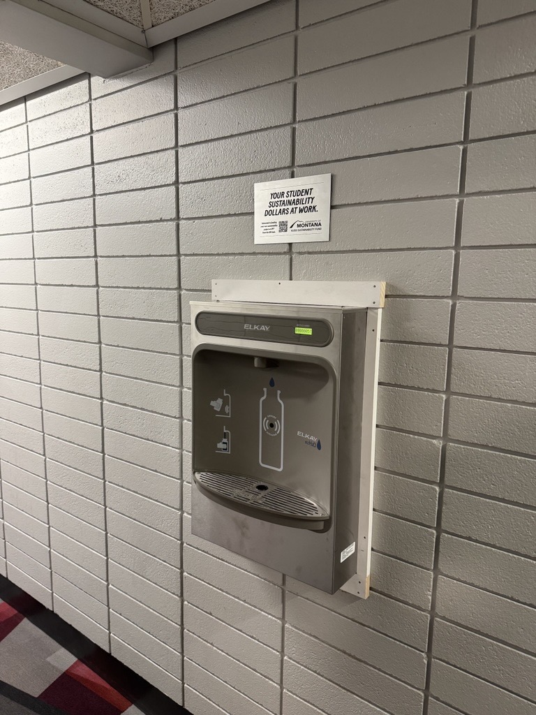 water bottle filler in a hallway with a silver kless plaque posted above