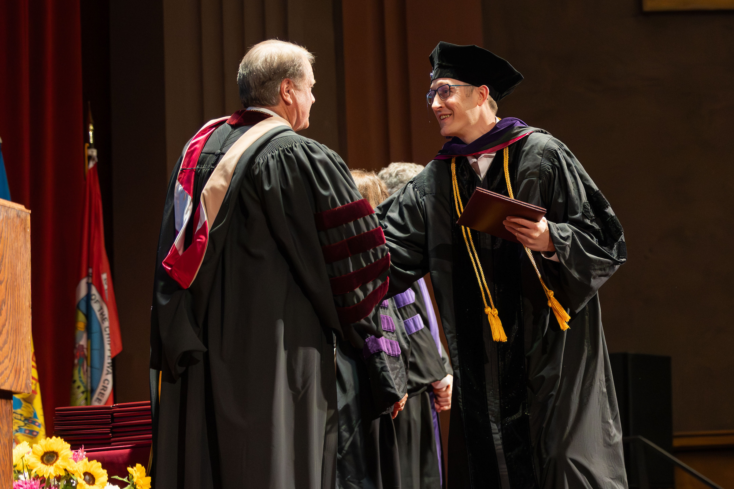 graduate shaking president of UM's hand while accepting diploma