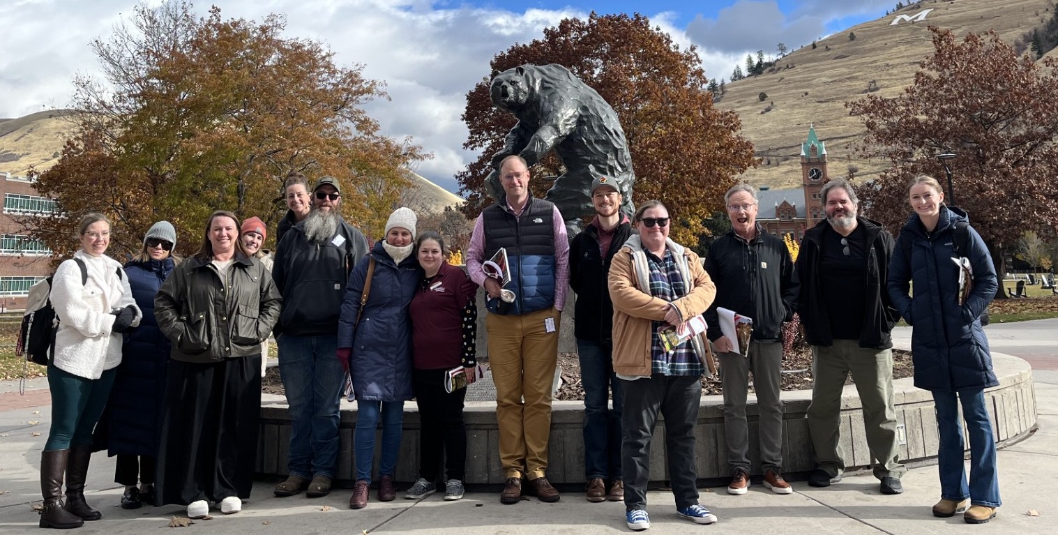 group of people standing in front of griz statue on the UM oval