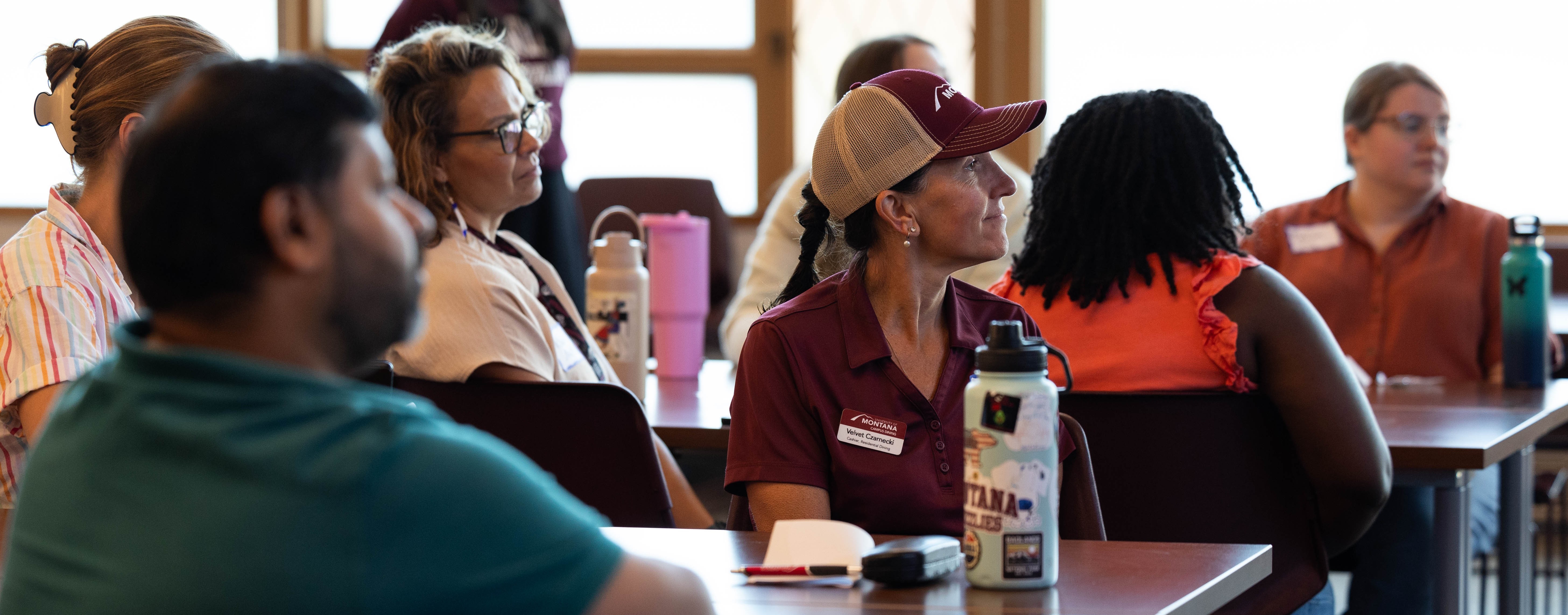group of people seated at tables looking at a presentation off to the right