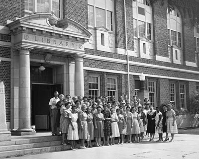 Historic black and white photograph of a large group of people, presumably library staff and visitors, posing in front of a library building.