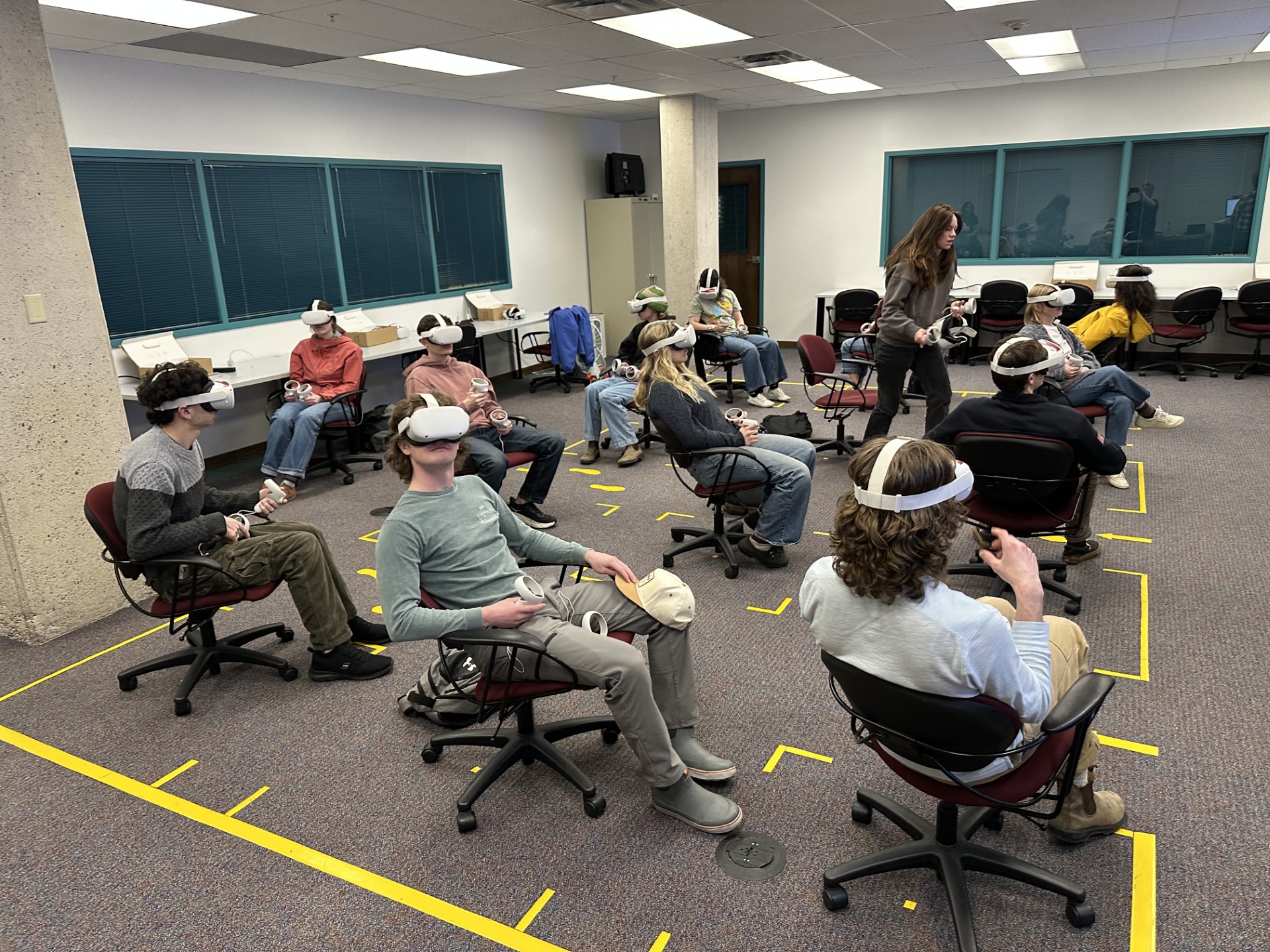 Image showing numerous students wearing VR headsets seated in chairs inside of the Buckhous Immersive Learning Space at the Mansfield Library