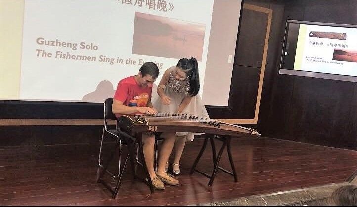 PGO China student plays a guzheng instrument.