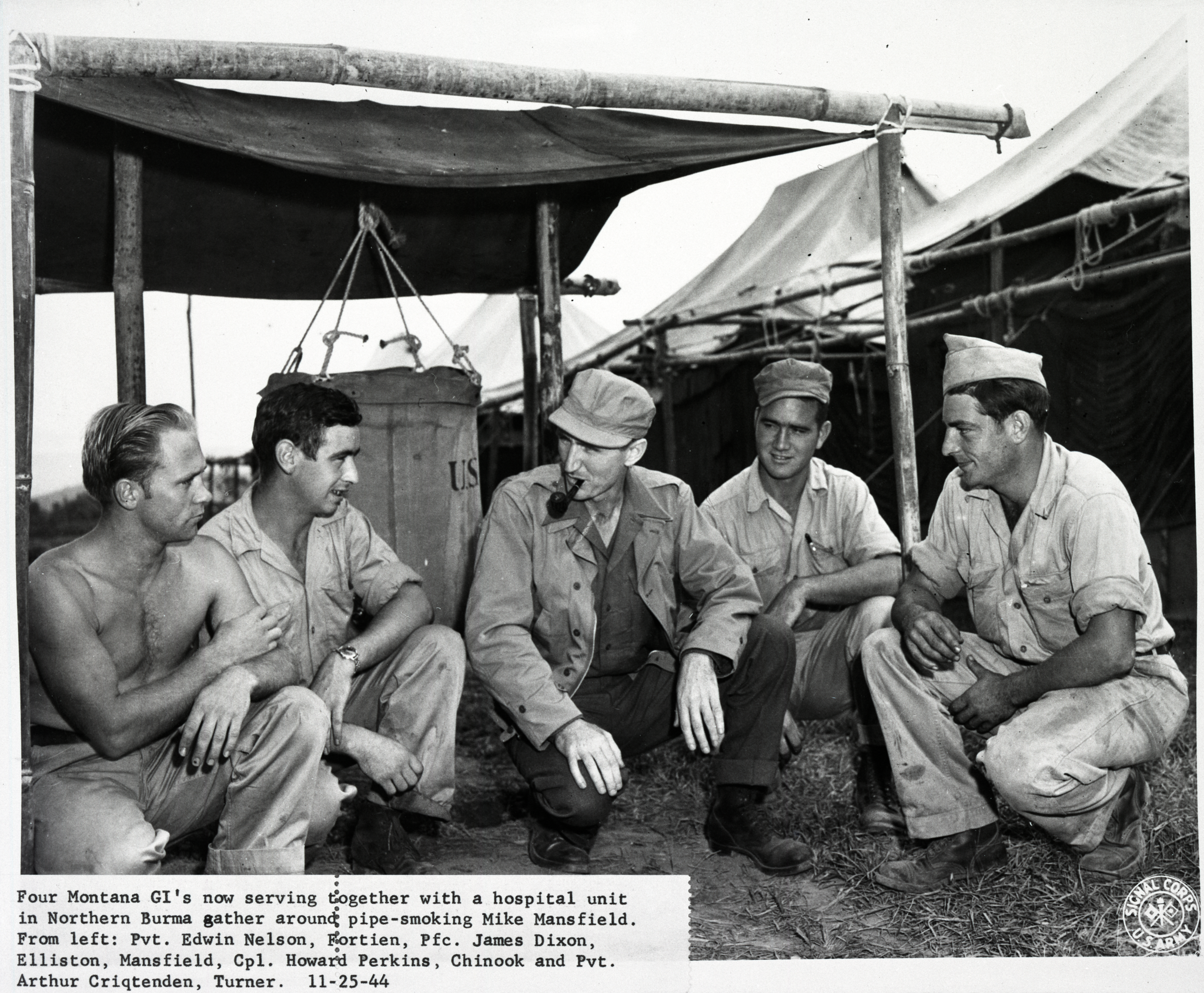Four GI's from Montana in 1944 Northern Burma gather around a pipe smoking Mike Mansfield