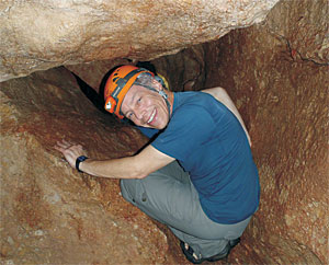 UM Archaeologist John Douglas climbs through a narrow point in the entrance of the Actun Tunichil Muknal cave. 