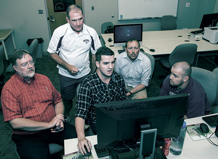 Joel Henry (second from left) helps demonstrate software donated by Symantec to UM. Henry’s own software helps search troves of legal textual data.