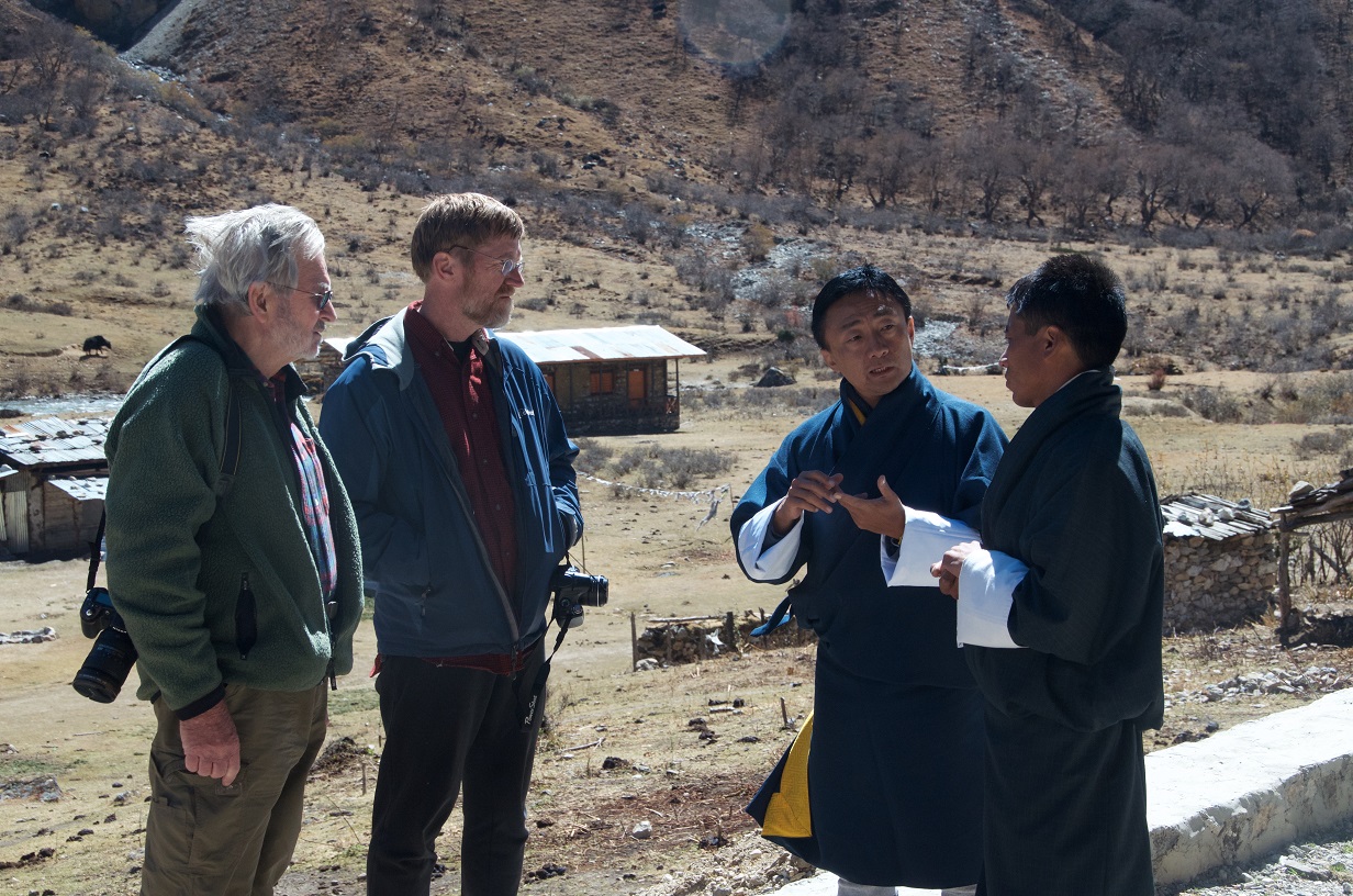 Photo of four people standing and talking in the field