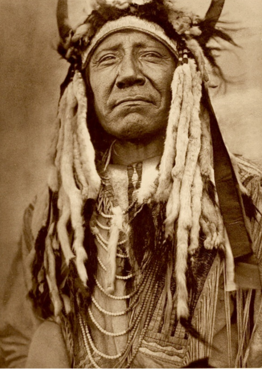 Photo of Winter white ermine pelts drape chief Two Moons headdress. 