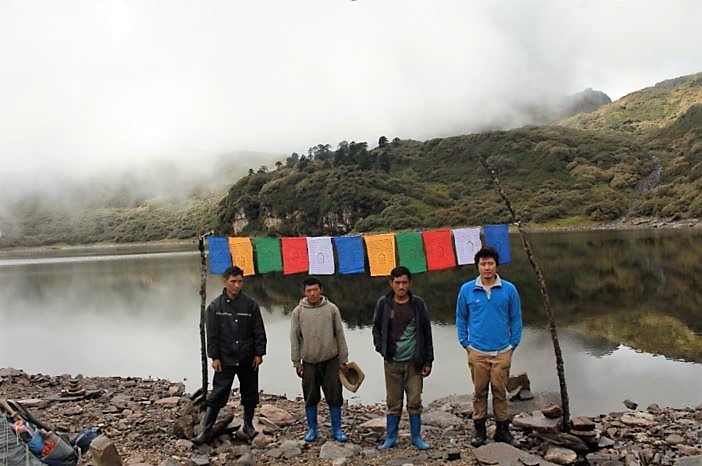 Photo of four people standing on the shore in front of flags