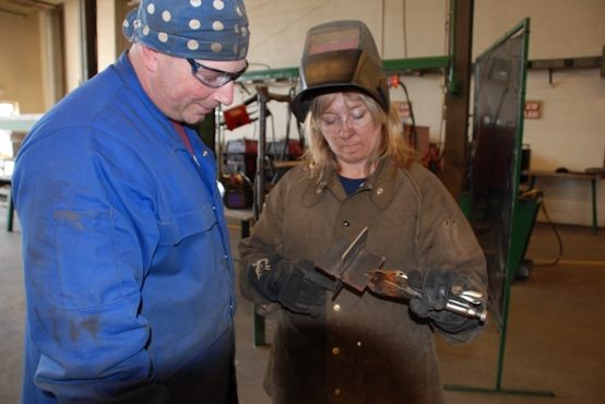 Instructor Zach Reddig leads student in weld