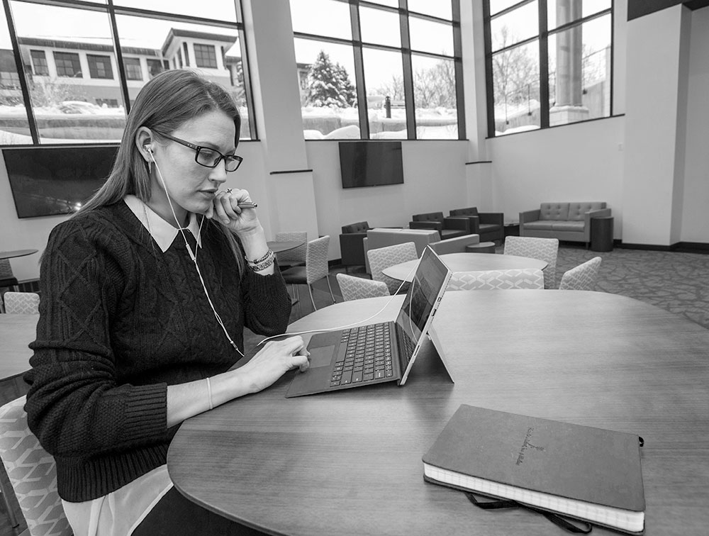 A UM student works at her laptop in the Gallagher Business Building.