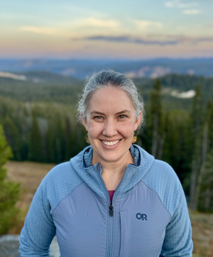 Dr. Blair Debuysscher standing on a mountain at sunset