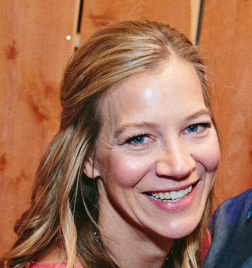 A smiling Kelly Dixon against a wooden background