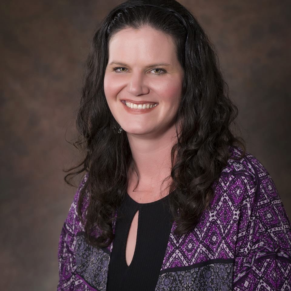 Professional portrait of Lisa Hunt with long dark hair smiling, wearing a purple patterned shawl.