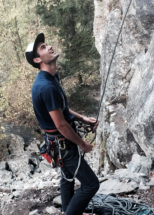 Bryson Allen looks up and smiles while rock climbing
